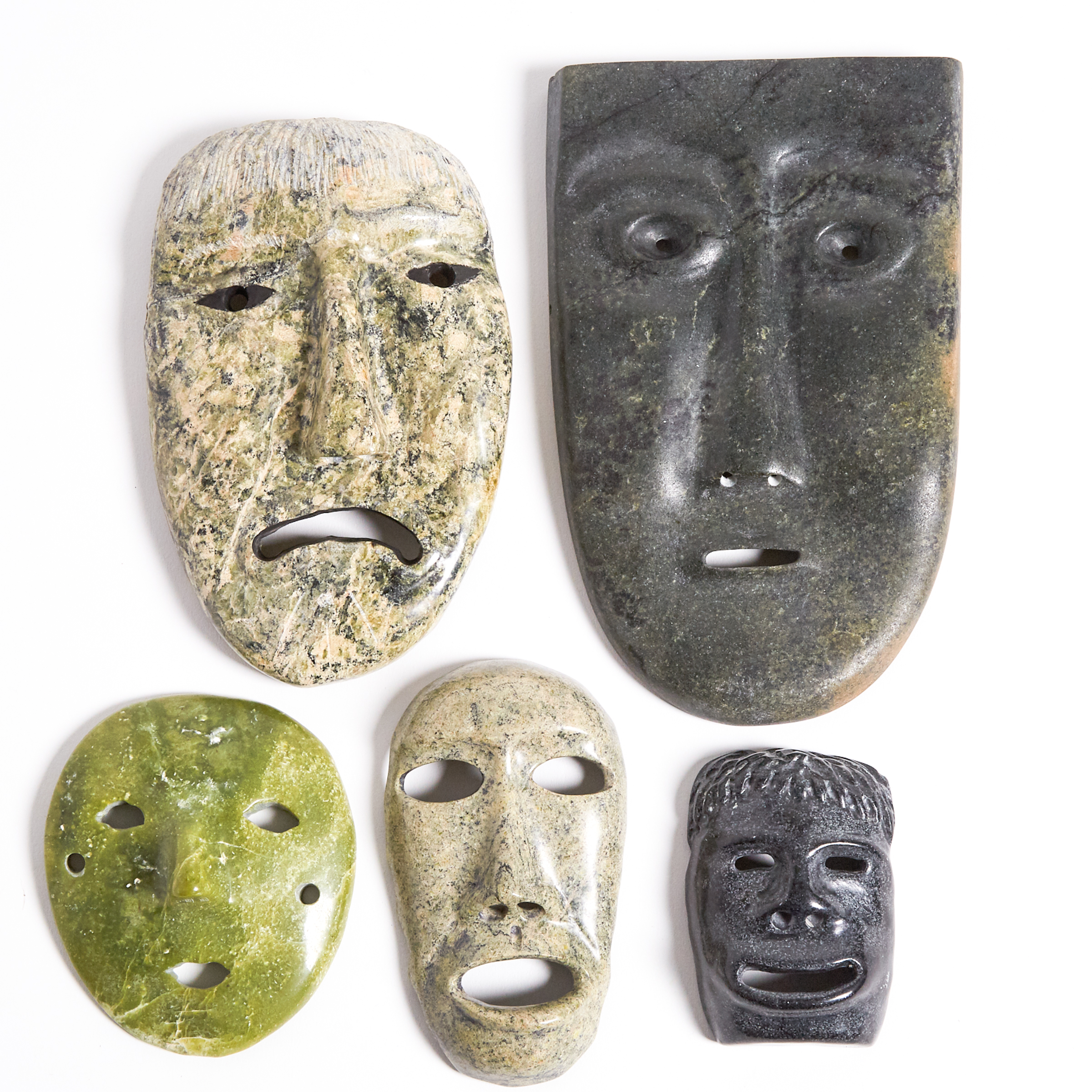A COLLECTION OF FIVE STONE CARVED MASKS