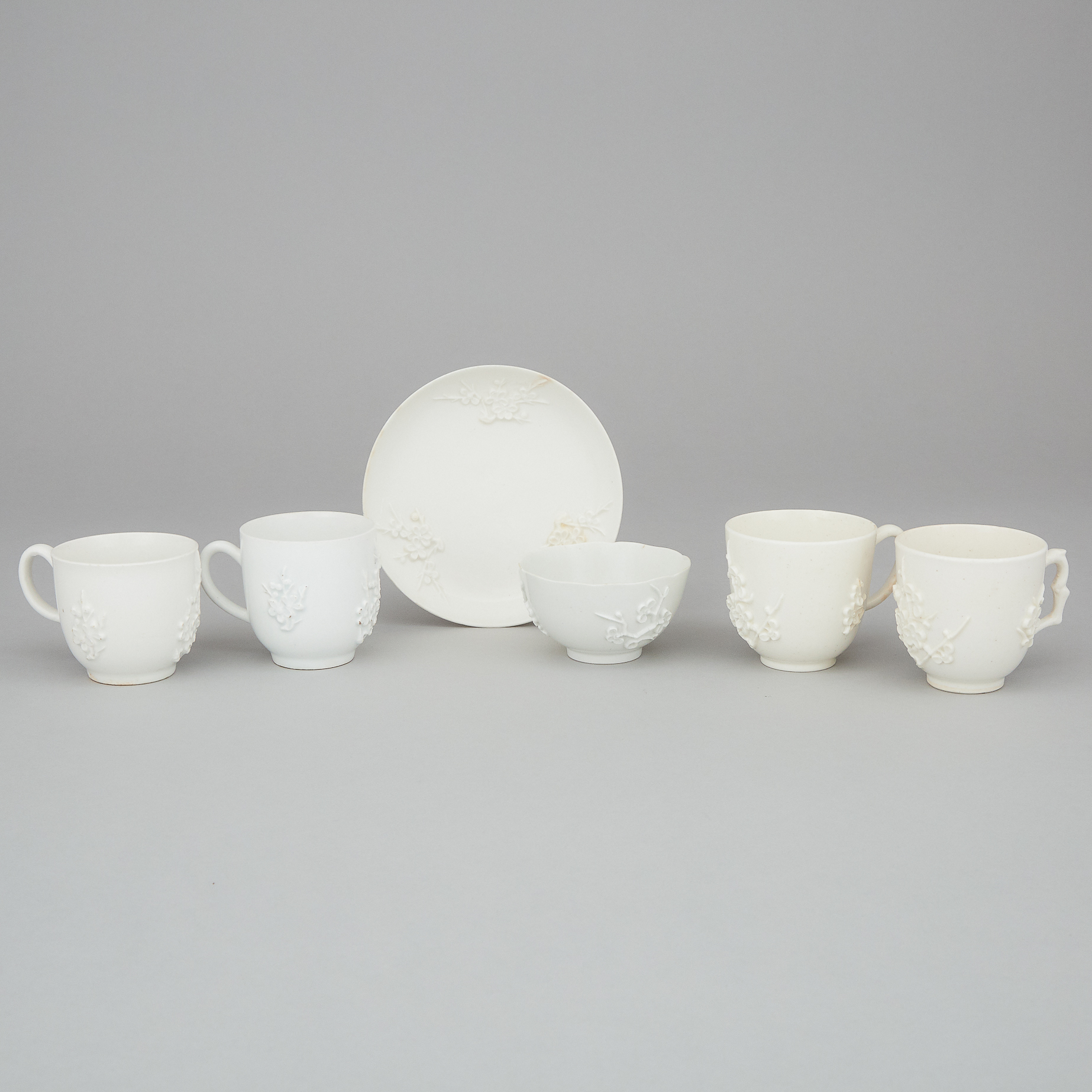 Four Bow Moulded and White Glazed Prunus Cups and a Tea Bowl and Saucer, c.1755